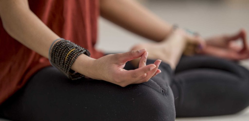 Meditation Pose A teenage girl is indoors in a fitness studio. She is sitting cross-legged and meditating. The picture is focused on her lower body.